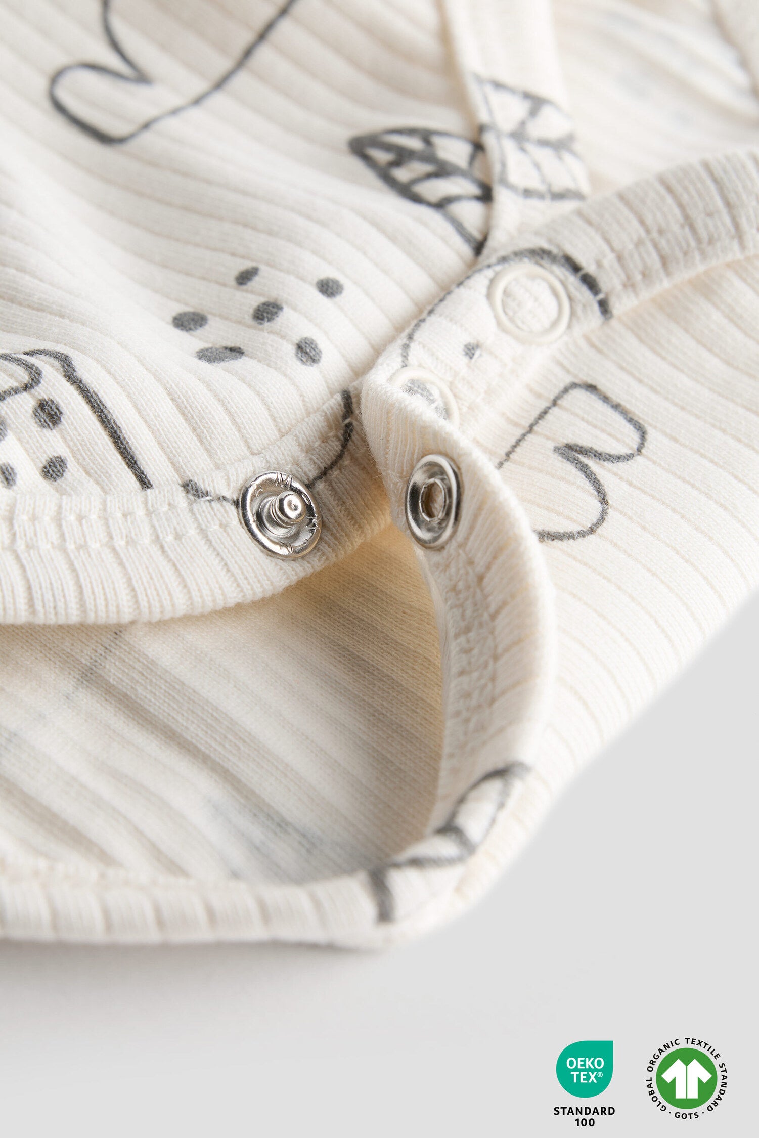 Close-up of a baby romper with butterfly patterns and buttons on a light background.