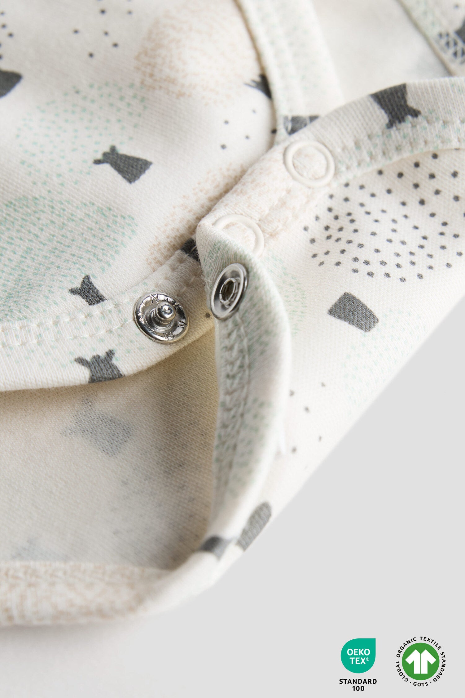 Close-up of a baby outfit with buttons and a pattern on a white background