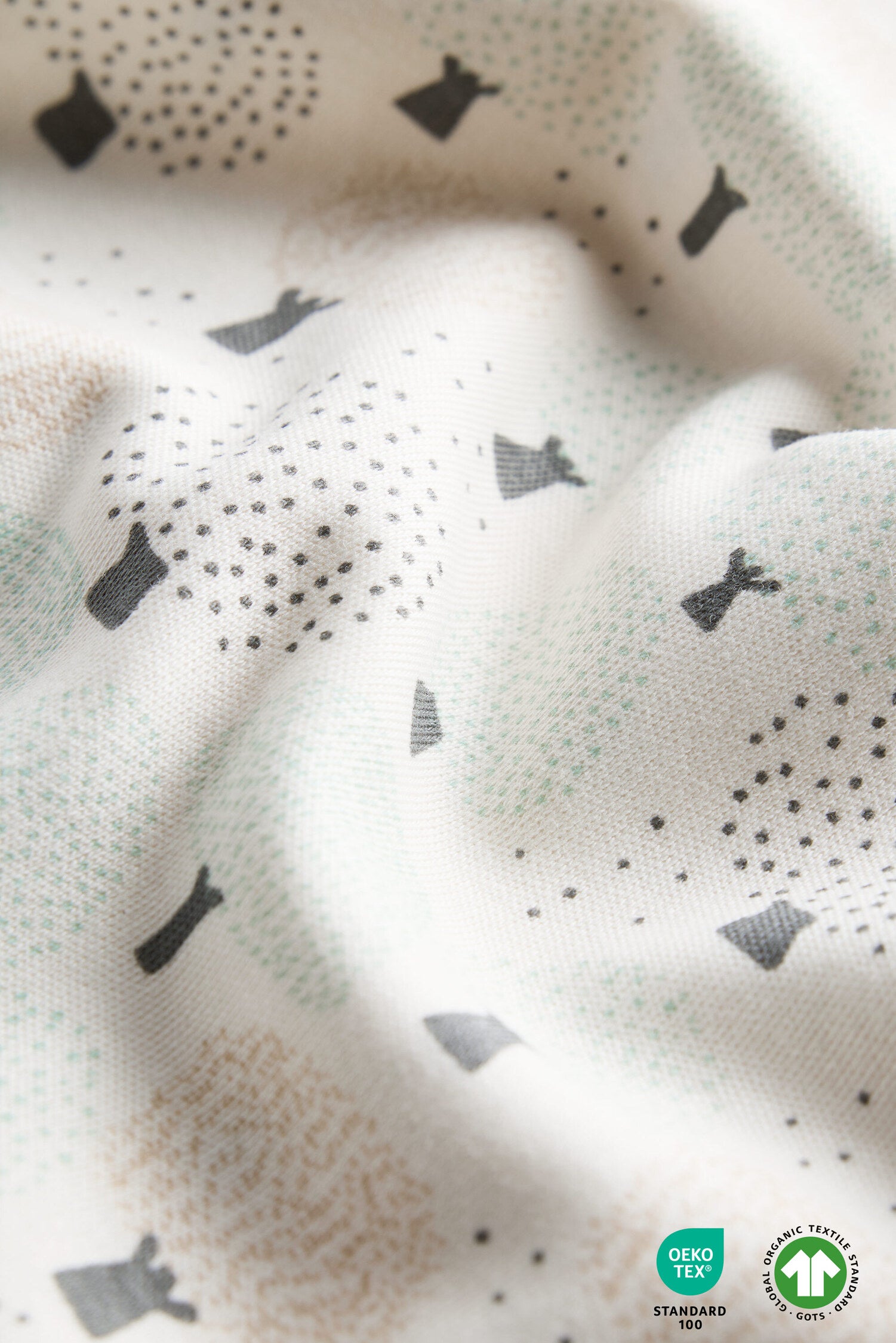 Textured fabric with black shapes and dots on a neutral background