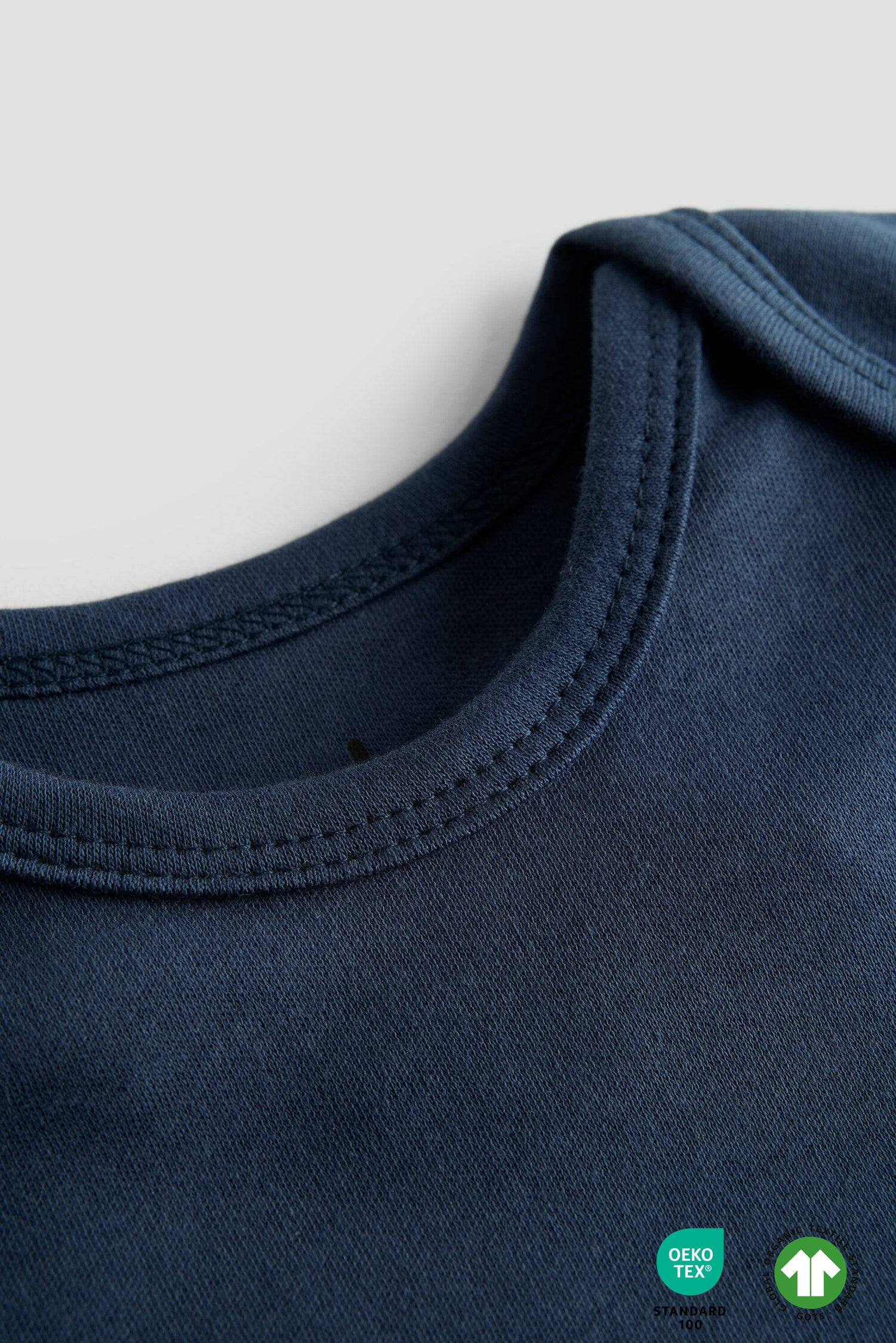 Close-up of a navy blue garment with a brand label on a light gray background