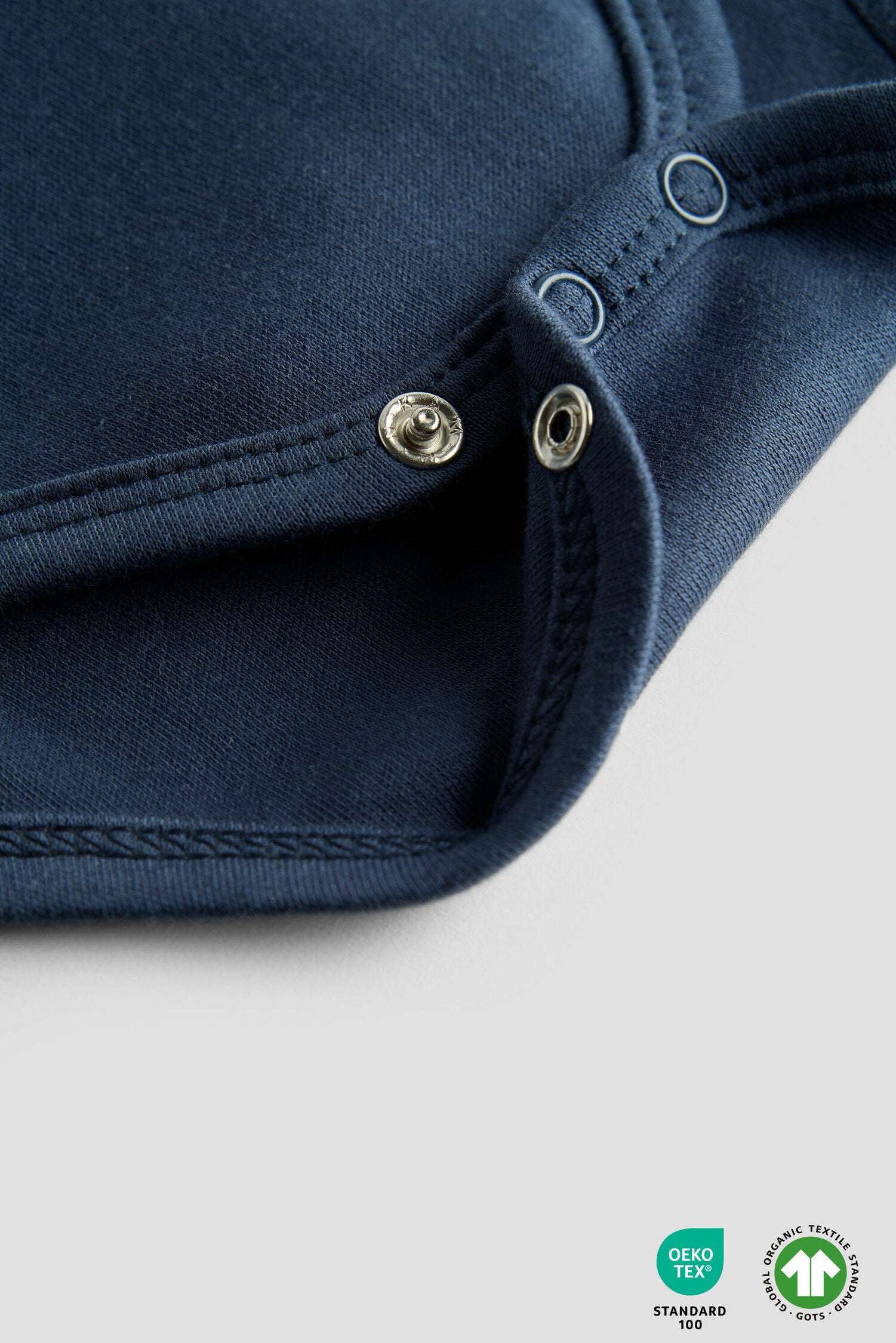 Close-up of a navy blue garment with button details on a light gray background