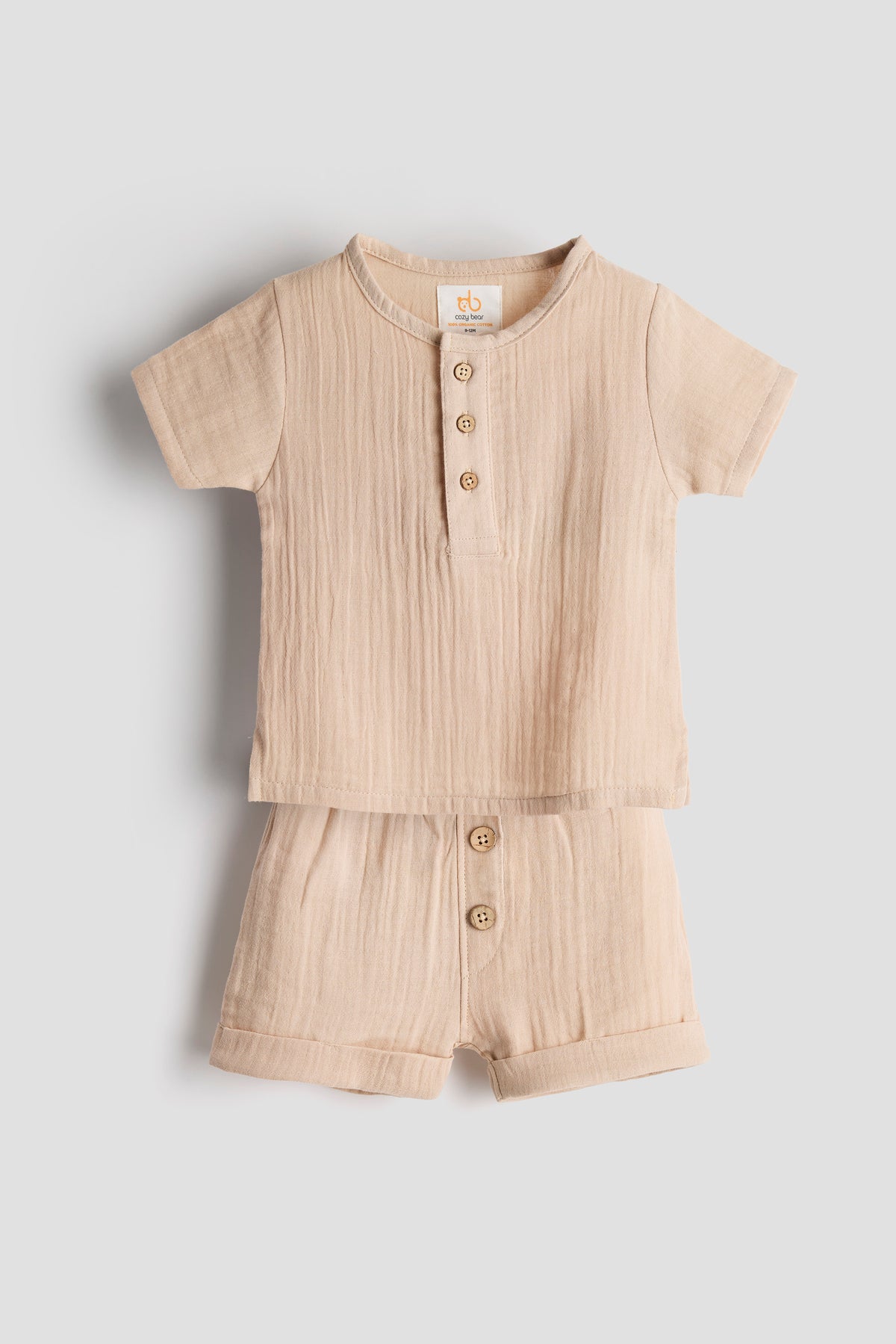 Beige baby romper with buttons on a light gray background