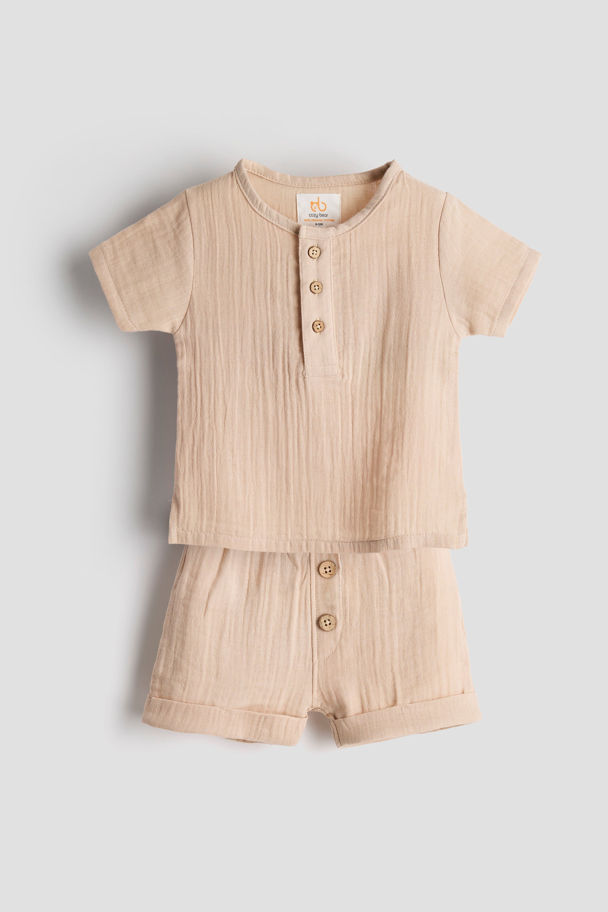 Beige baby romper with buttons on a light gray background