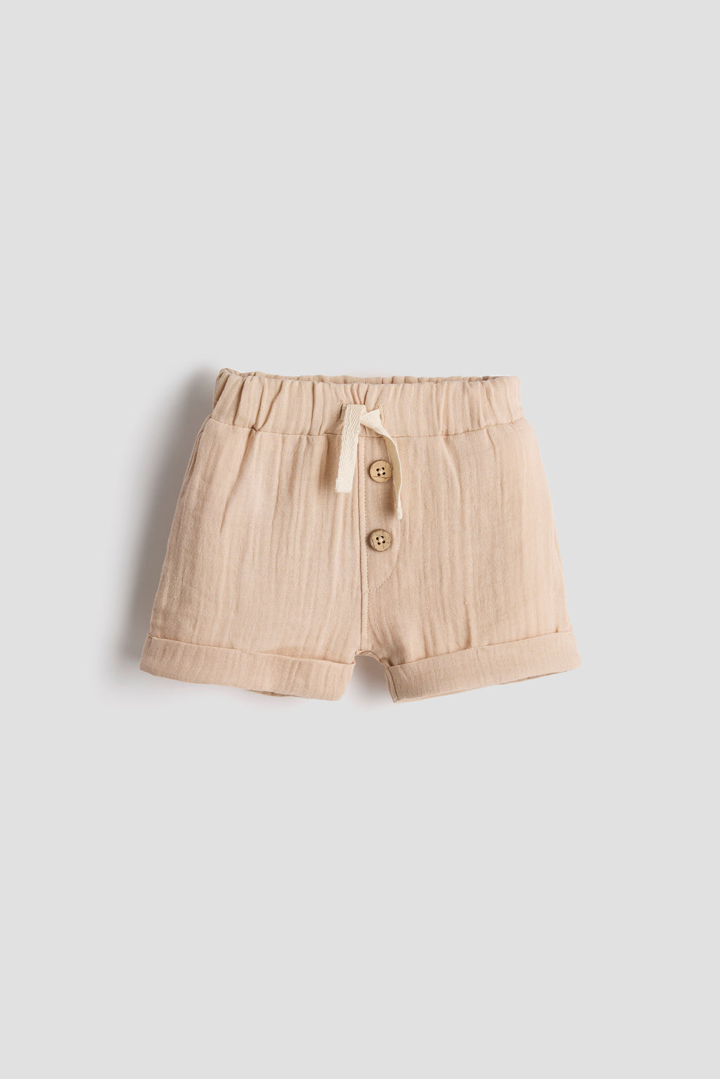 Beige shorts with buttons on a light gray background