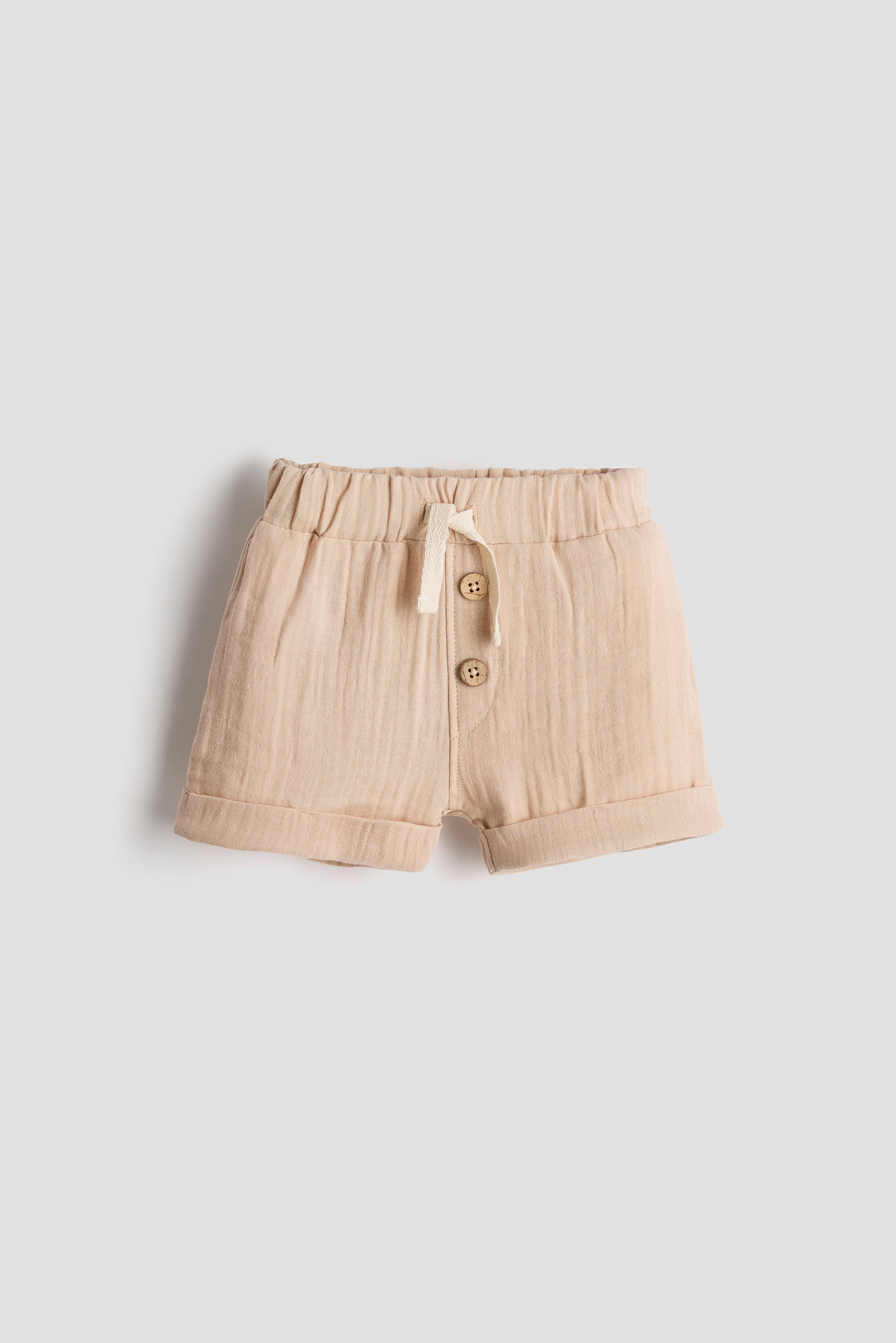 Beige shorts with buttons on a light gray background