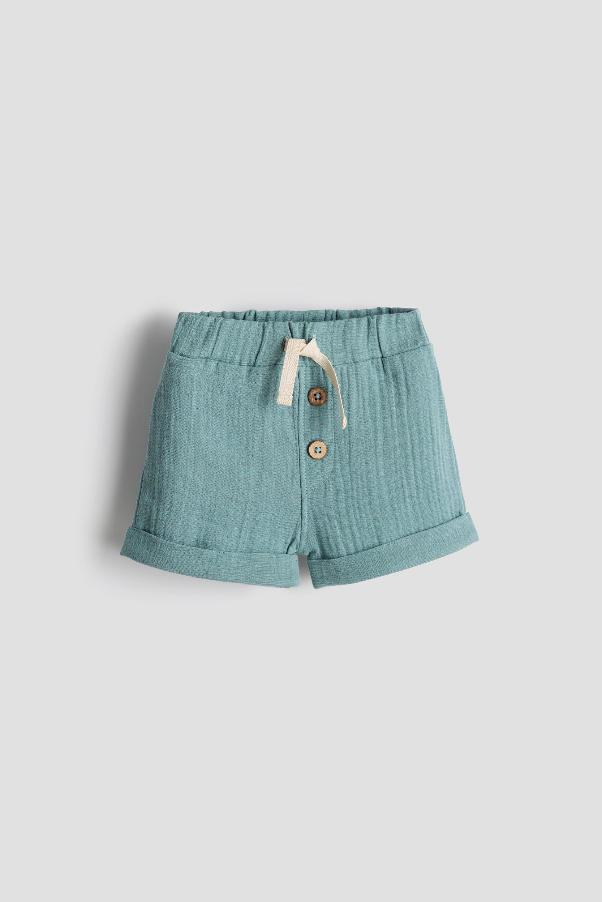 Light blue shorts with buttons on a light gray background