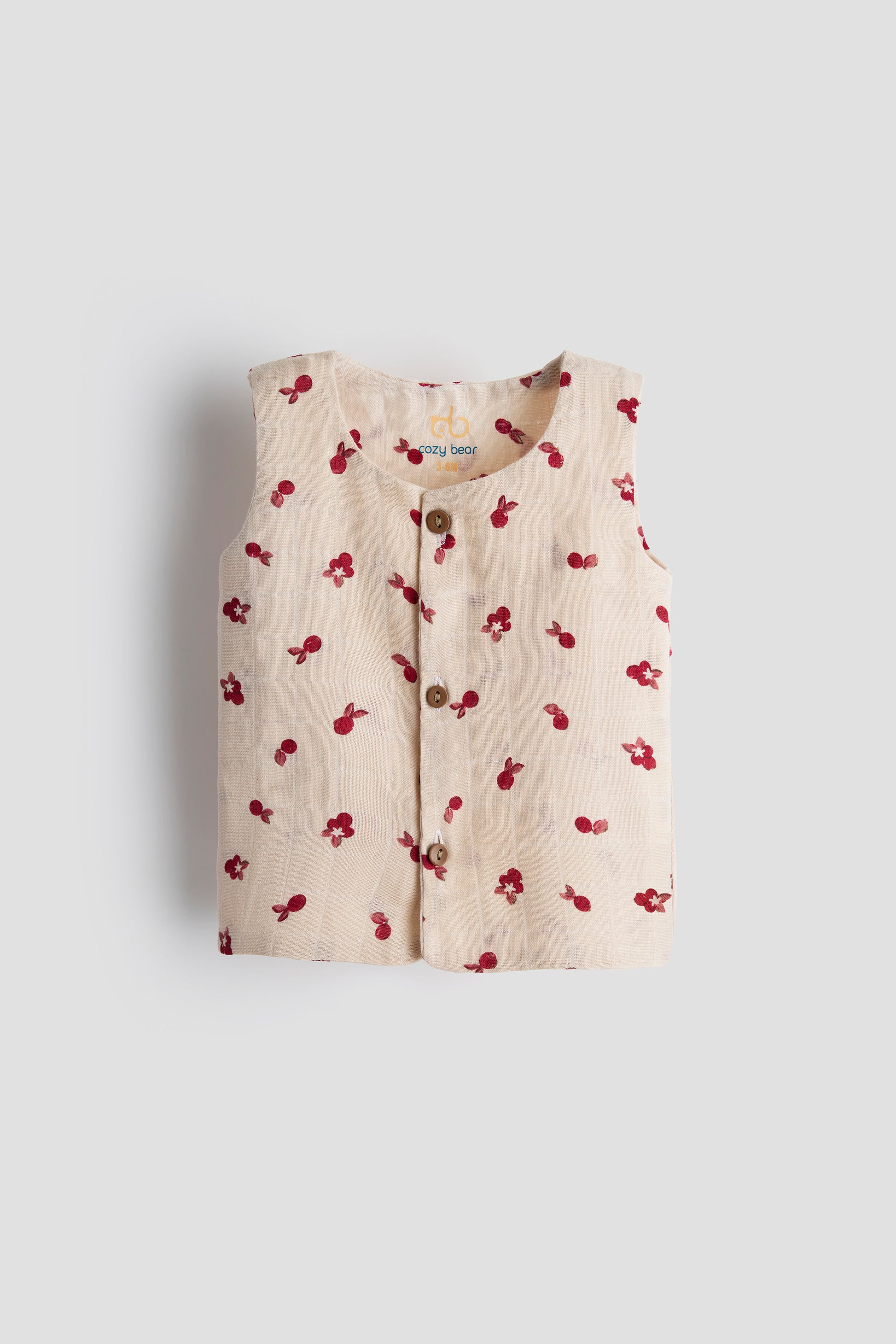 Beige sleeveless top with red floral pattern on a light gray background
