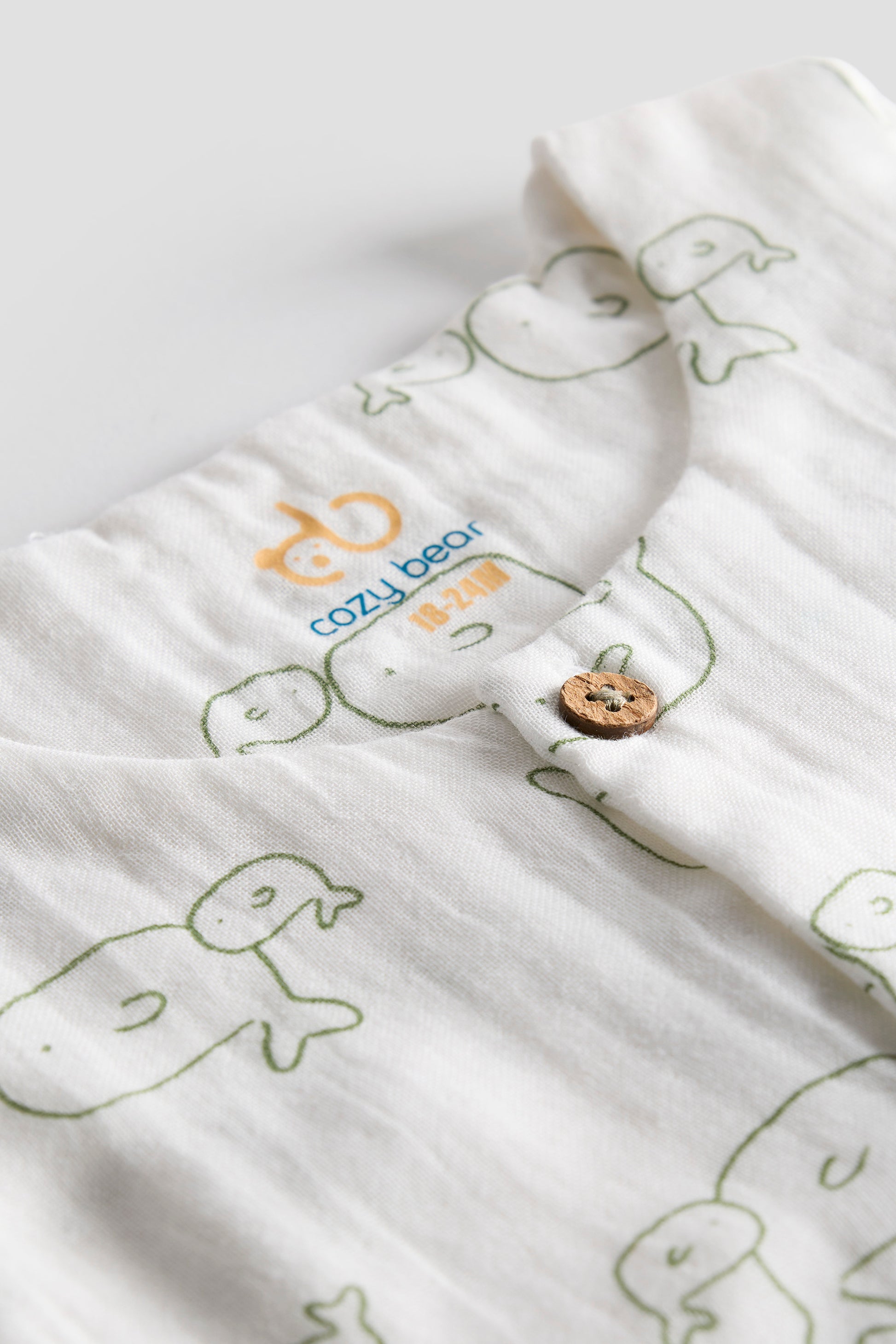 White fabric with green whale patterns and a tag on a white background